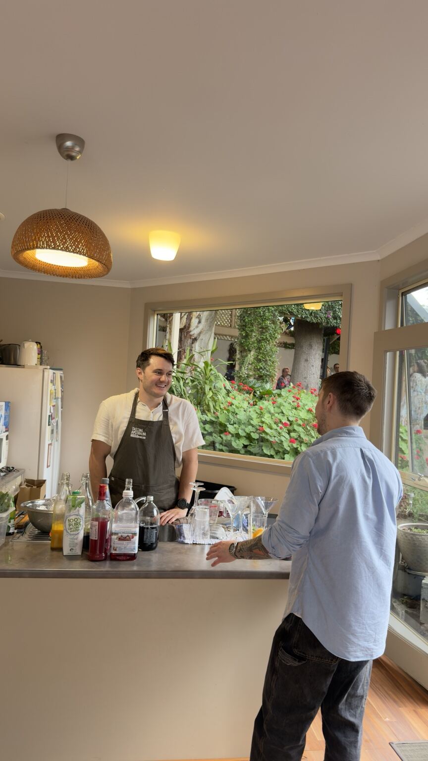 A bartender sharing a laugh with a guest across an indoor home bar